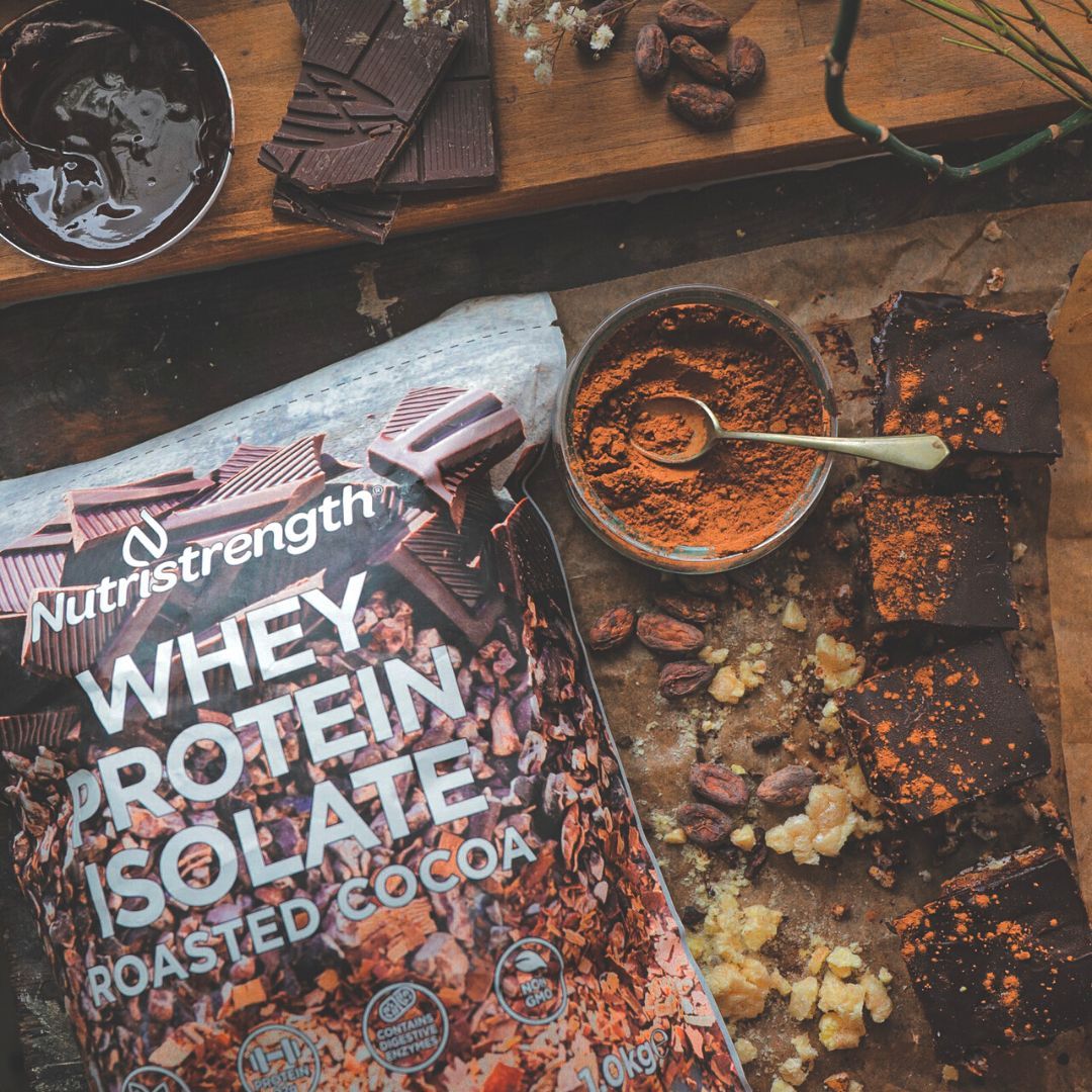 Nutristrength's new & improved Chocolate Whey Protein Isolate in it's compostable eco-friendly packaging next to home-made rice cakes