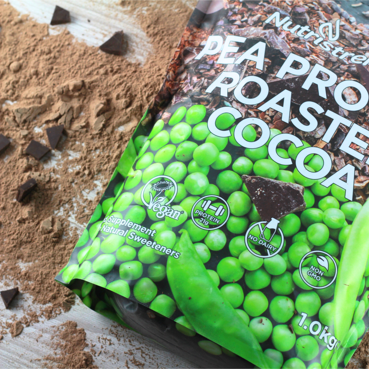 Packaging of pea protein roasted cocoa mix with green peas and chocolate pieces on a wooden surface.