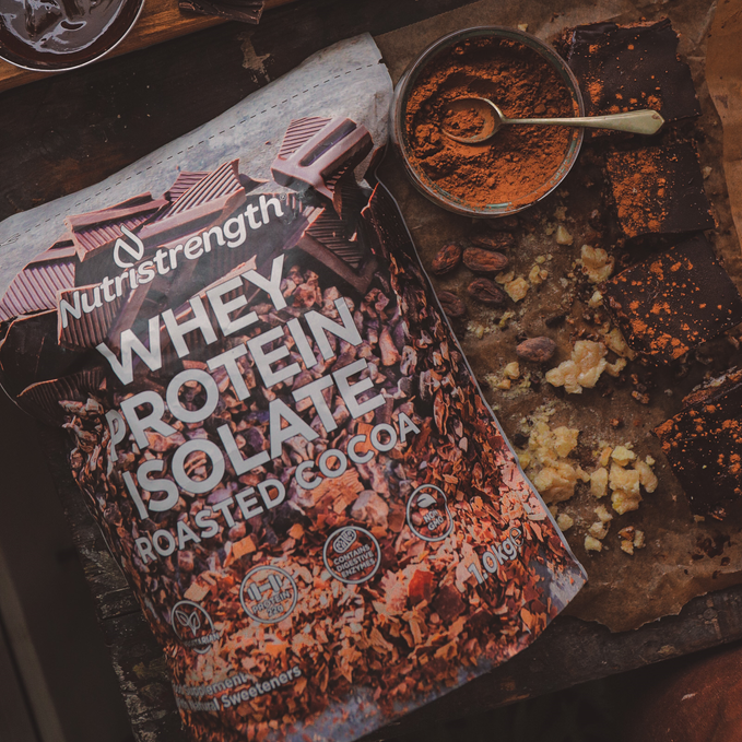 Nutristrength Chocolate Whey Protein Isolate in a new compostable pouch on a background of high protein chocolate rice cakes and the ingredients used for them